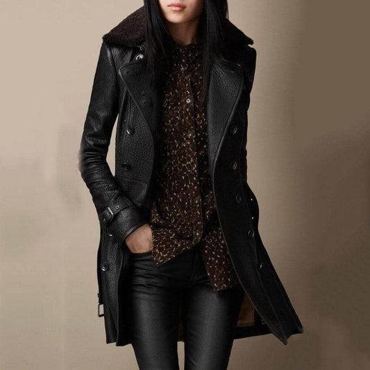 Kvinde iført sort dobbeltbrystet frakke med shearling krave og beltet manchetter, stylet med bukser og transparent bluse._0
