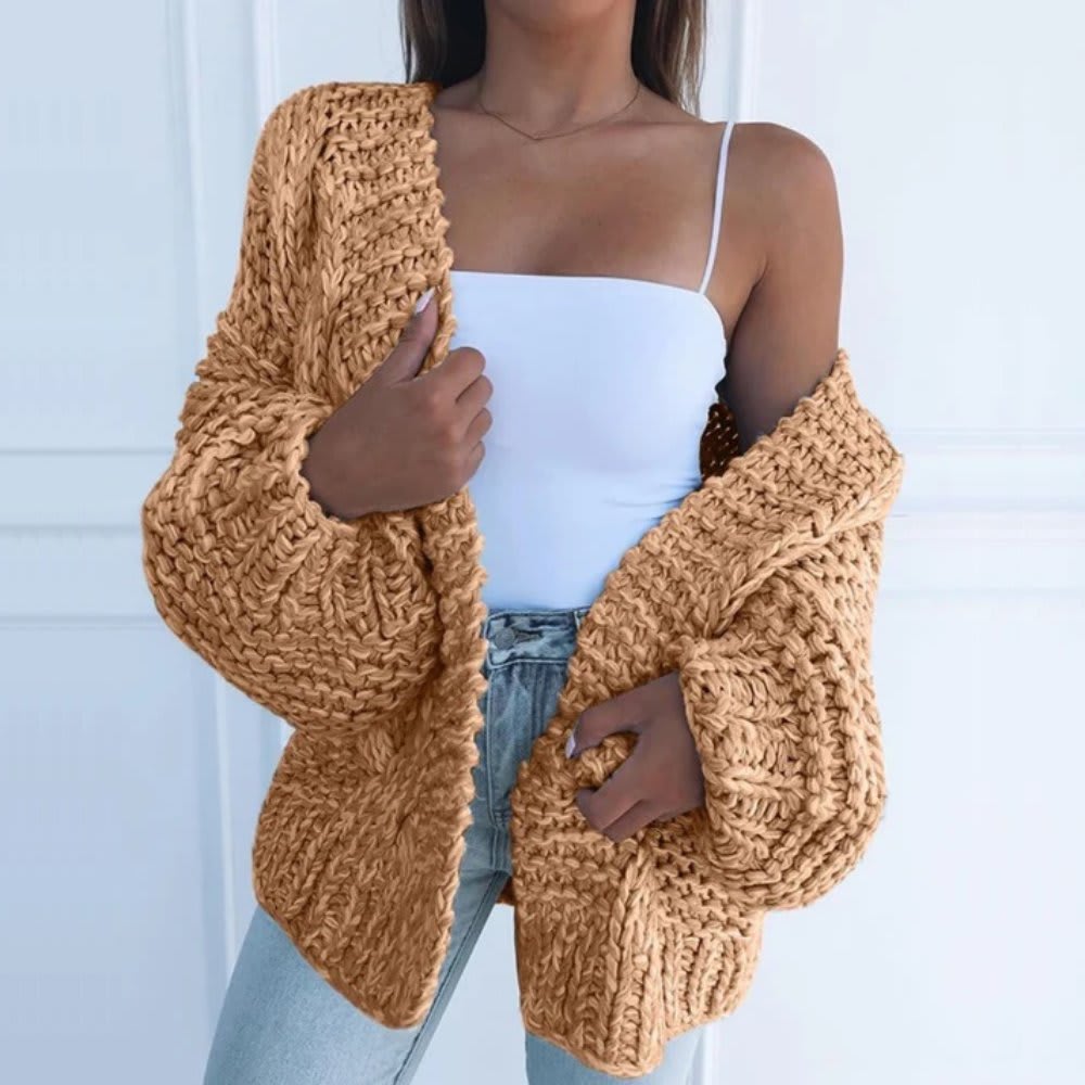 Kvinde iført hvid top, lyse jeans og en sort grovstrikket cardigan med åben front og brede ærmer._5