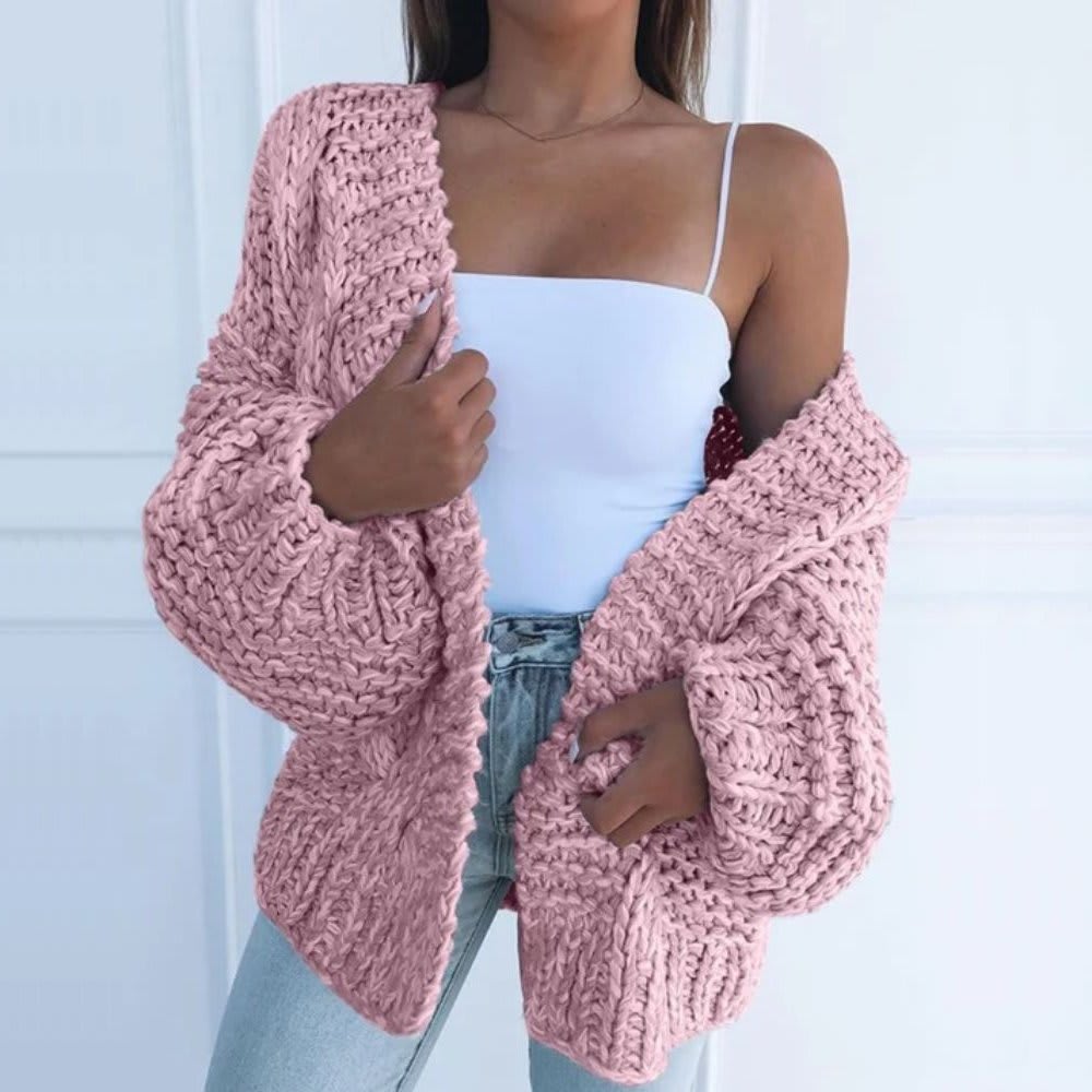 Kvinde iført hvid top, lyse jeans og en sort grovstrikket cardigan med åben front og brede ærmer._6