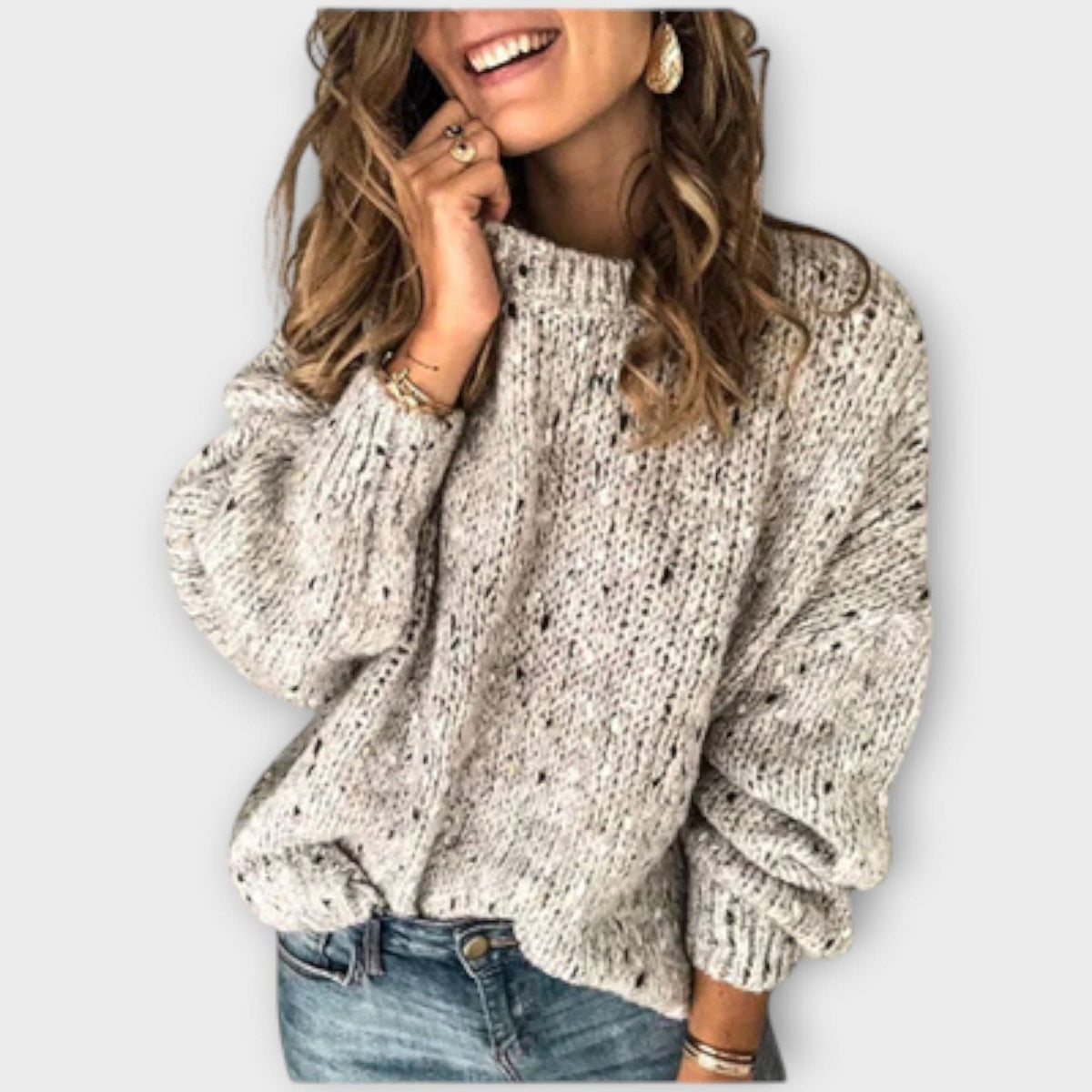 Kvinde iført en grovstrikket beige sweater med høj hals og løs pasform, stylet med lyse jeans._0