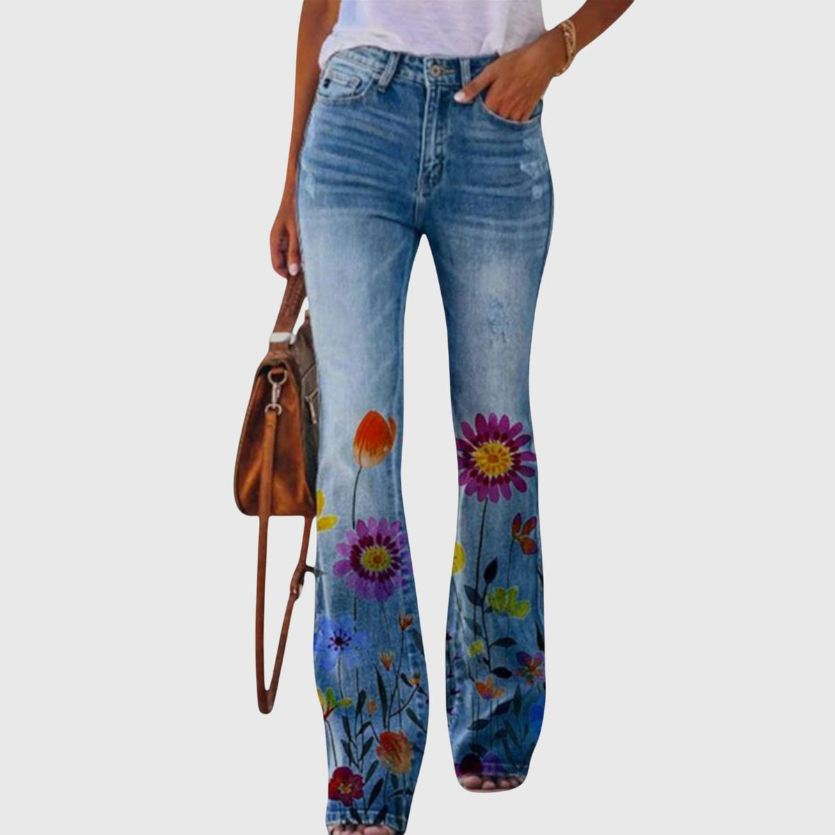 Kvinde iført jeans med vid pasform og farverige blomstermotiver, der går fra taljen og ned langs benene._0