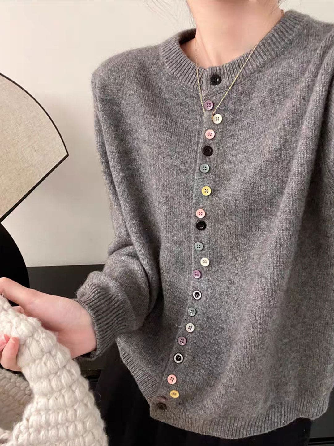 Kvinde iført grå cardigan med crew neck og farverige knapper ned foran._0
