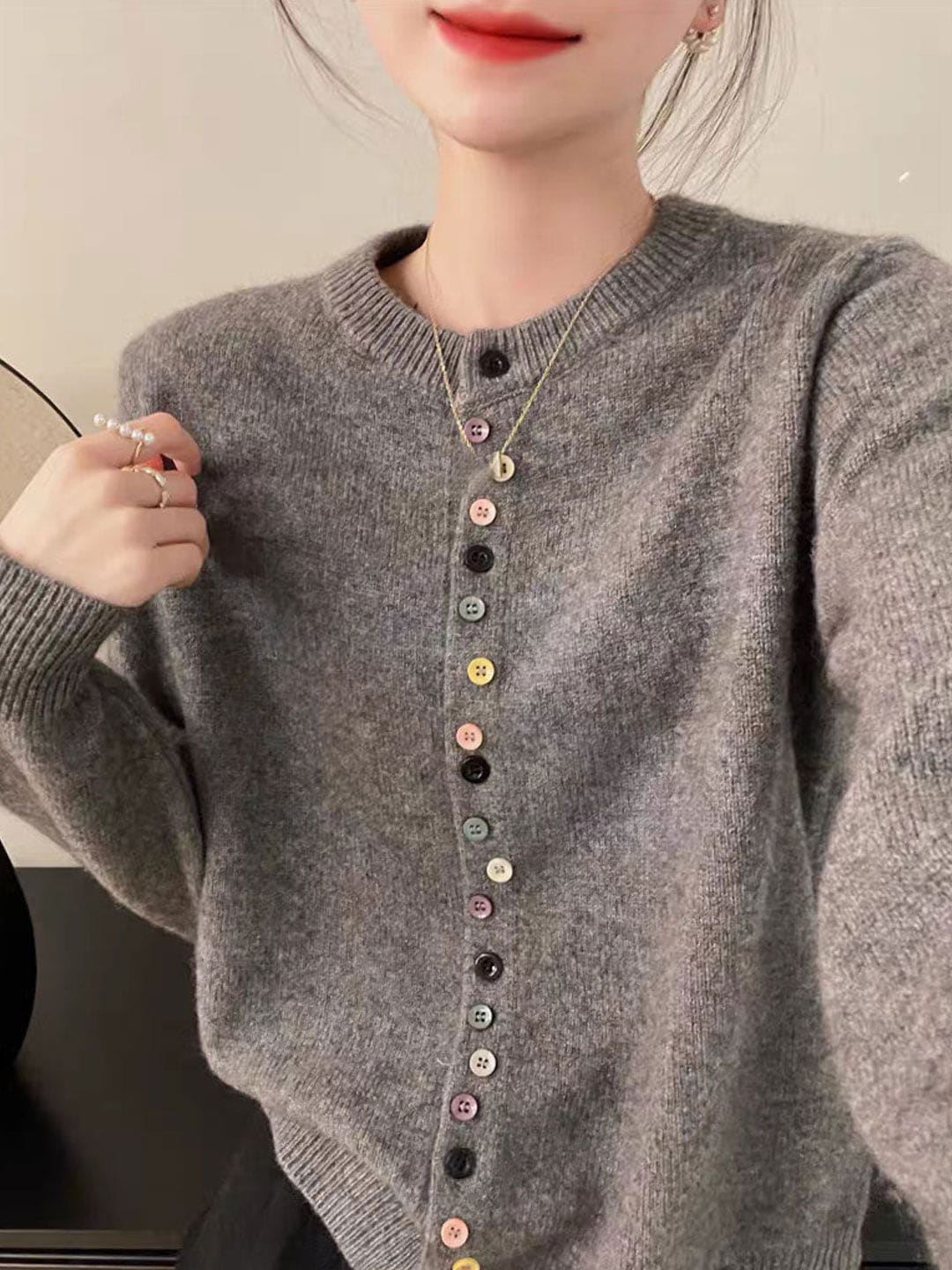 Kvinde iført grå cardigan med crew neck og farverige knapper ned foran._1