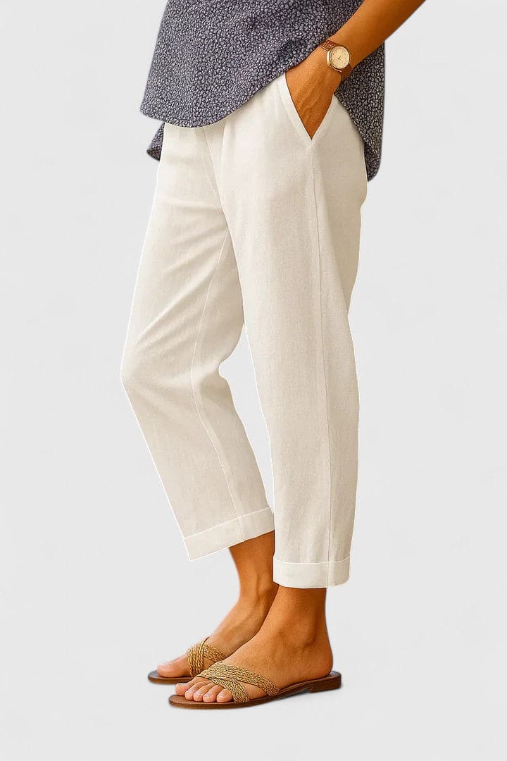 Kvinde bærer beige bukser med afslappet pasform og opslag, stylet med et mørkegrå mønstret skjorte, et guldur og sandaler._0