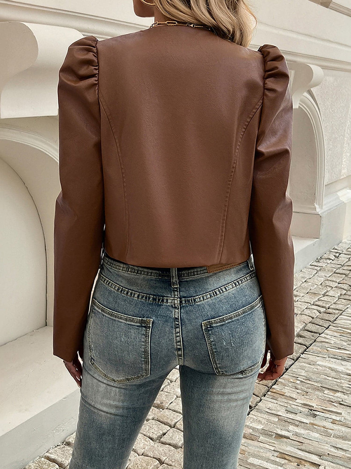 Kvinde iført kort blazer med pufærmer og åben front, stylet med hvid top og jeans_1