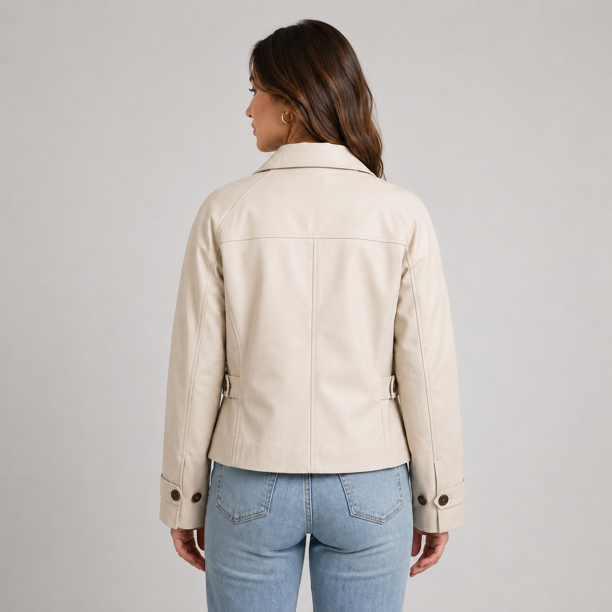 Kvinde iført kort beige jakke med knapper foran og klassisk krave, stylet med hvid top og lyseblå jeans_1