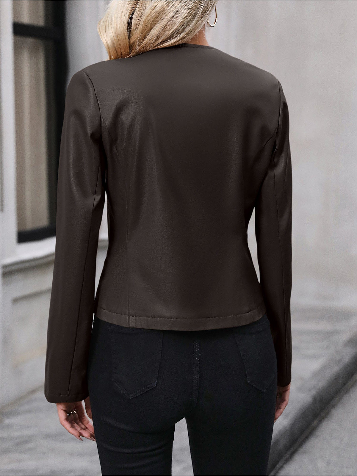 Kvinde iført sort kort jakke med lynlås foran, stylet med sort crop top og sorte bukser i elegant indendørsmiljø._16