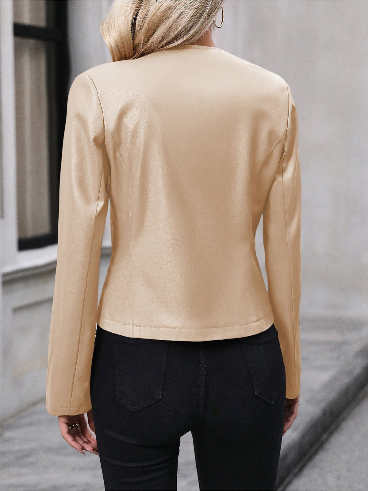 Kvinde iført sort kort jakke med lynlås foran, stylet med sort crop top og sorte bukser i elegant indendørsmiljø._19