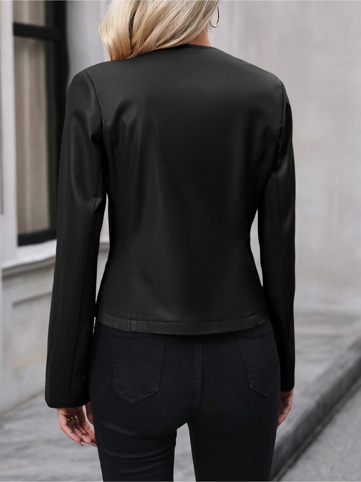 Kvinde iført sort kort jakke med lynlås foran, stylet med sort crop top og sorte bukser i elegant indendørsmiljø._4