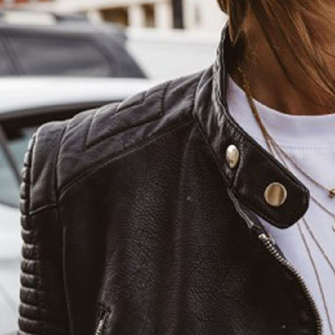 Kvinde iført en kort motojakke med asymmetrisk lynlås, quiltede skulderpaneler og snap-krave, stylet med hvid t-shirt og jeans._2