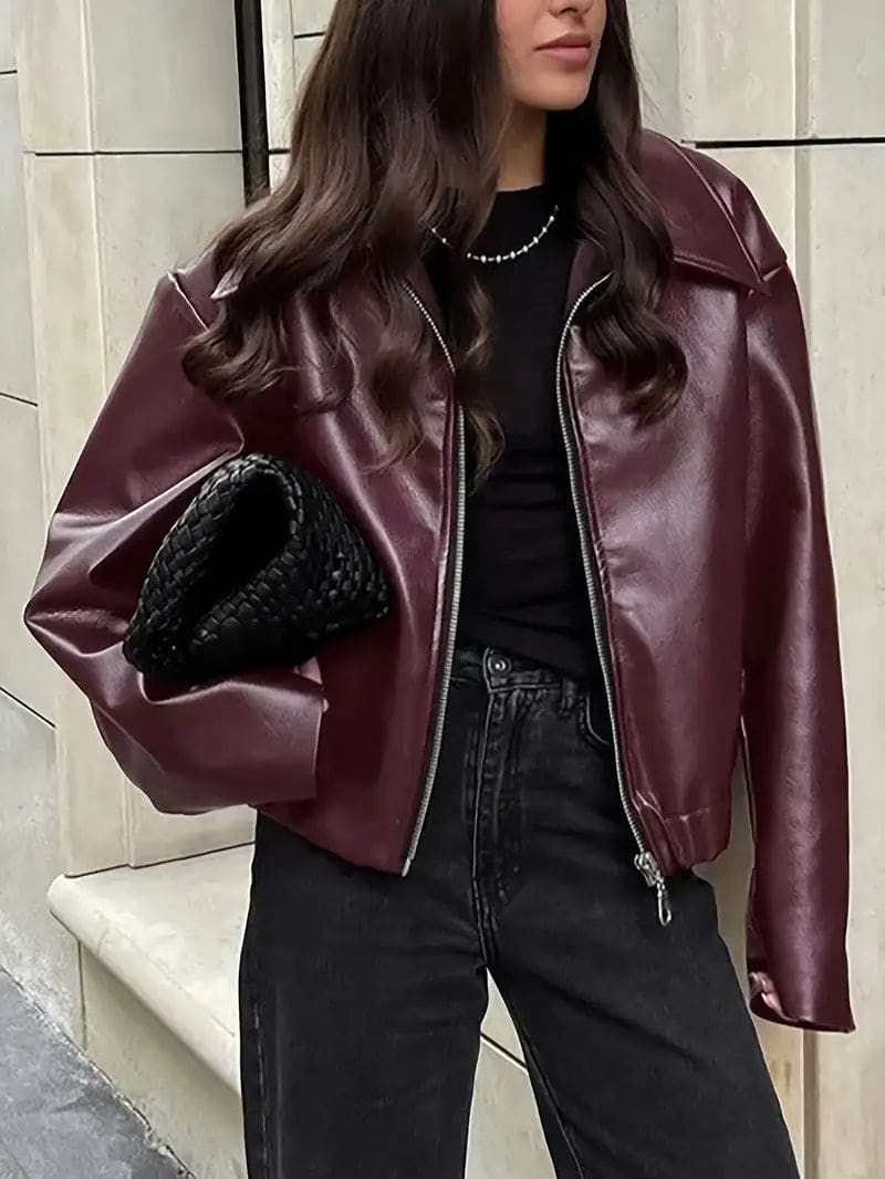 Kvinde iført kort jakke med krave og lynlås i burgundy nuance, stylet med sort top og sorte jeans._0
