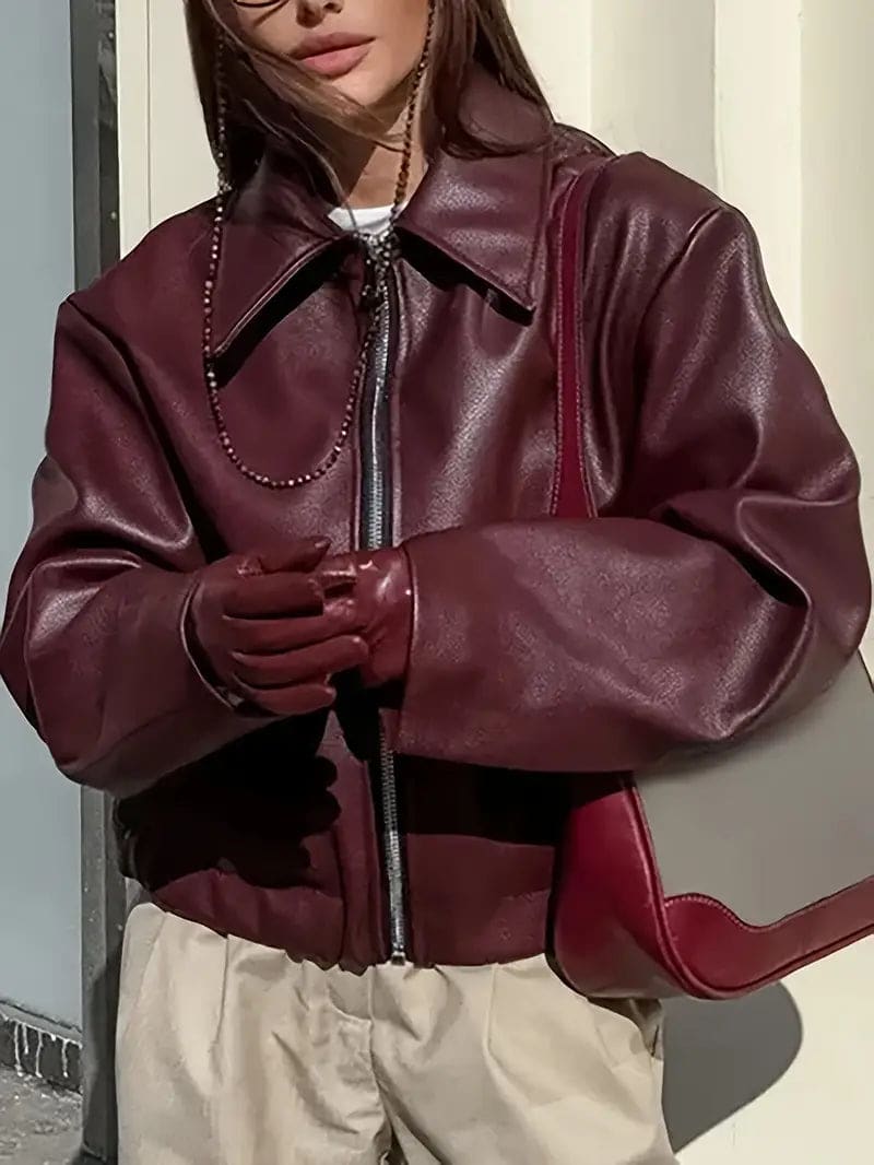 Kvinde iført kort jakke med krave og lynlås i burgundy nuance, stylet med sort top og sorte jeans._1
