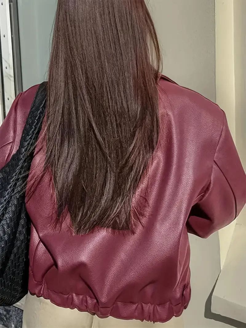 Kvinde iført kort jakke med krave og lynlås i burgundy nuance, stylet med sort top og sorte jeans._12
