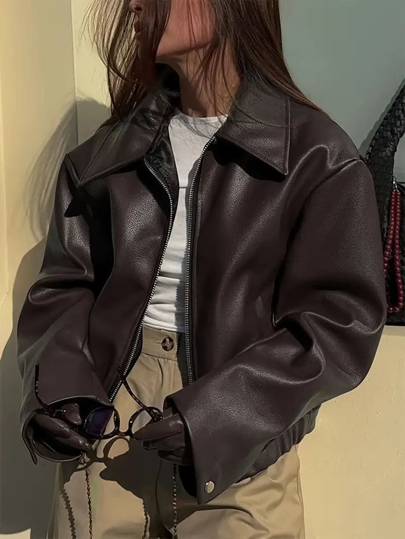 Kvinde iført kort jakke med krave og lynlås i burgundy nuance, stylet med sort top og sorte jeans._14