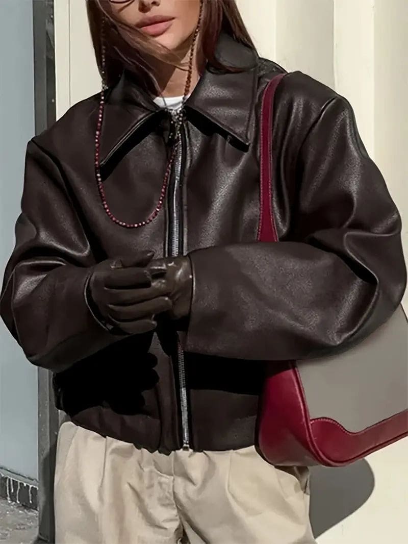 Kvinde iført kort jakke med krave og lynlås i burgundy nuance, stylet med sort top og sorte jeans._16