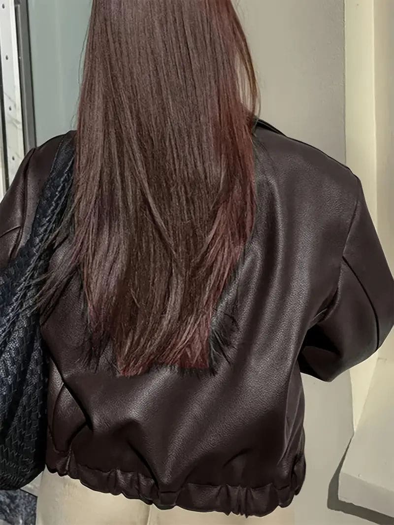 Kvinde iført kort jakke med krave og lynlås i burgundy nuance, stylet med sort top og sorte jeans._17