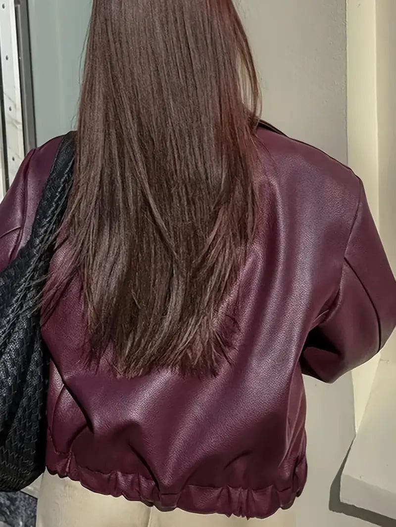 Kvinde iført kort jakke med krave og lynlås i burgundy nuance, stylet med sort top og sorte jeans._2