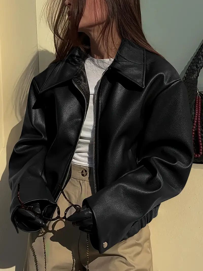 Kvinde iført kort jakke med krave og lynlås i burgundy nuance, stylet med sort top og sorte jeans._4