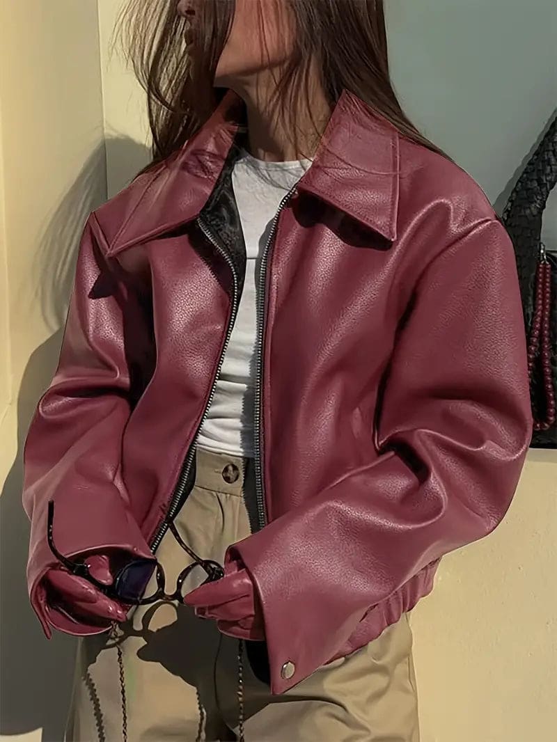 Kvinde iført kort jakke med krave og lynlås i burgundy nuance, stylet med sort top og sorte jeans._9