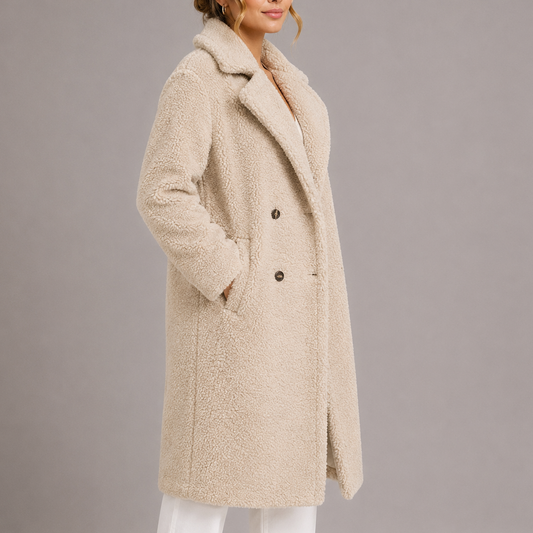 Kvinde iført lang beige teddy-frakke med dobbelt knappelukning og brede revers set forfra_1