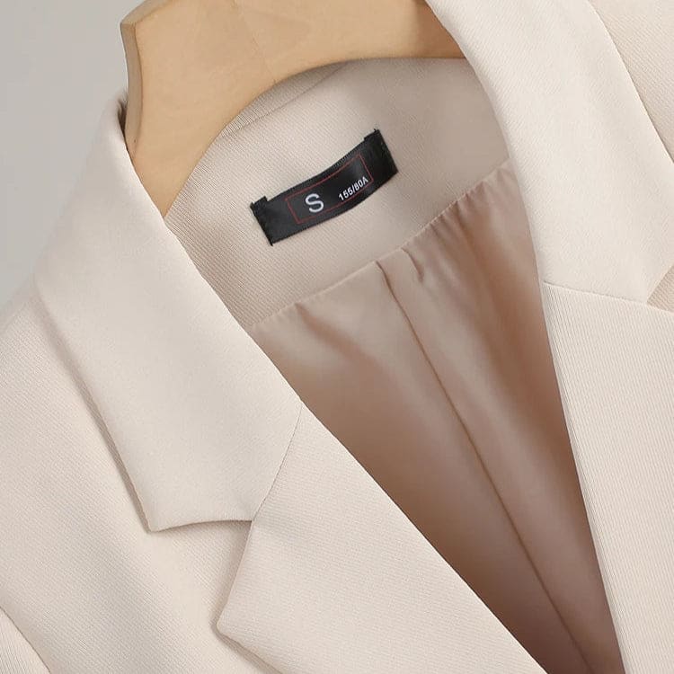 En figursyet blazer med klassiske revers, to knapper, klaplommer og knapdetaljer ved manchetterne på en bøjle._4