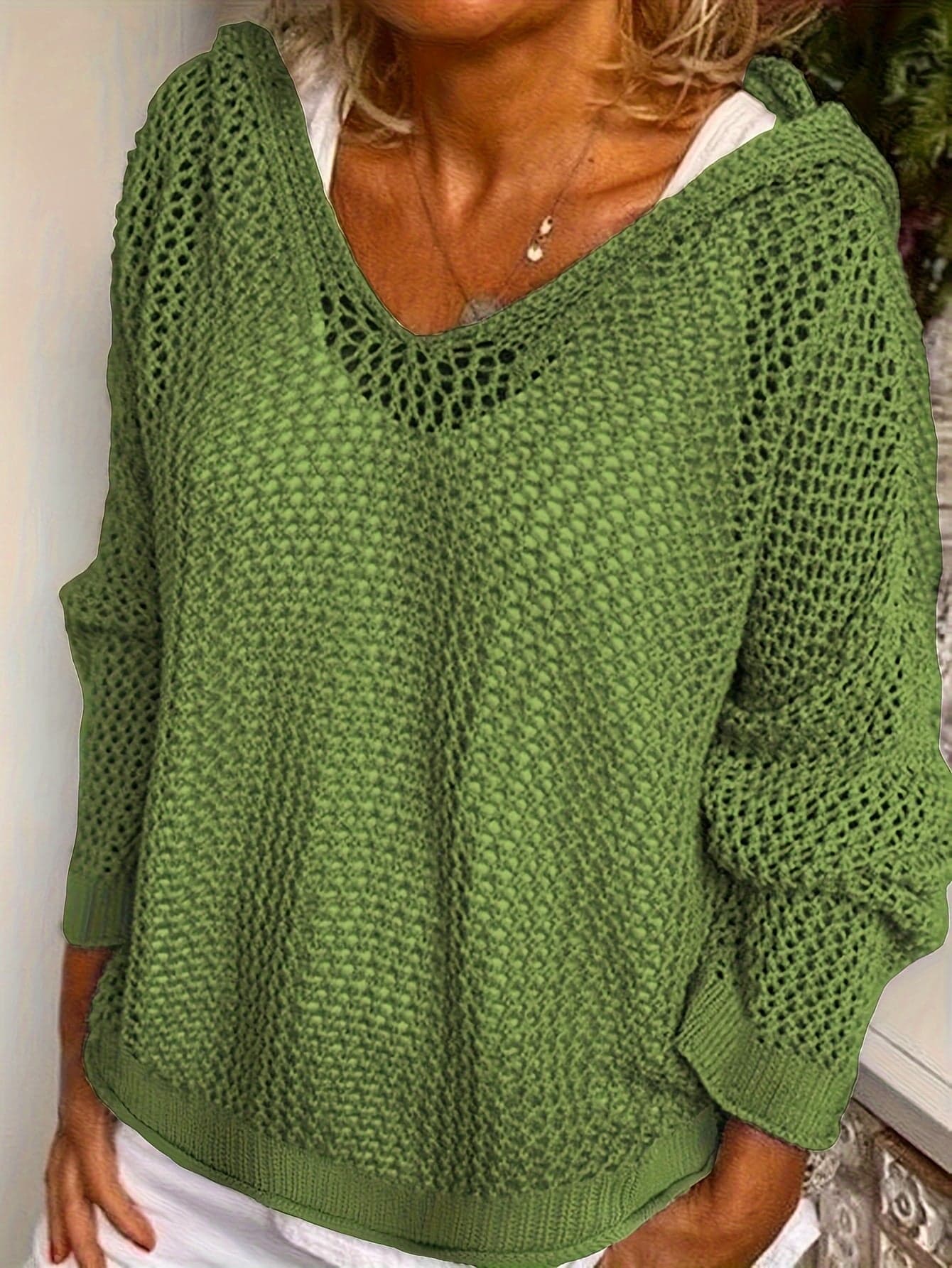 Kvinde iført en løst strikket sweater med åben struktur og hætte, stylet over en hvid bluse_1