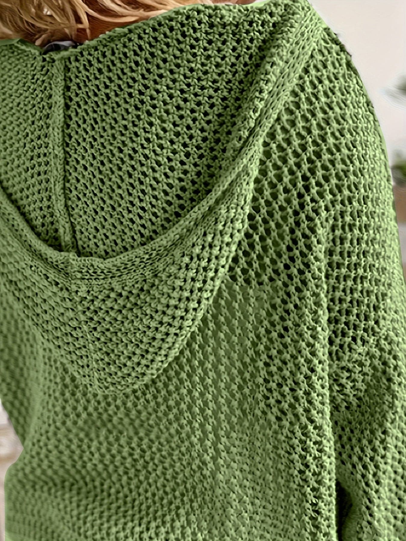 Kvinde iført en løst strikket sweater med åben struktur og hætte, stylet over en hvid bluse_5