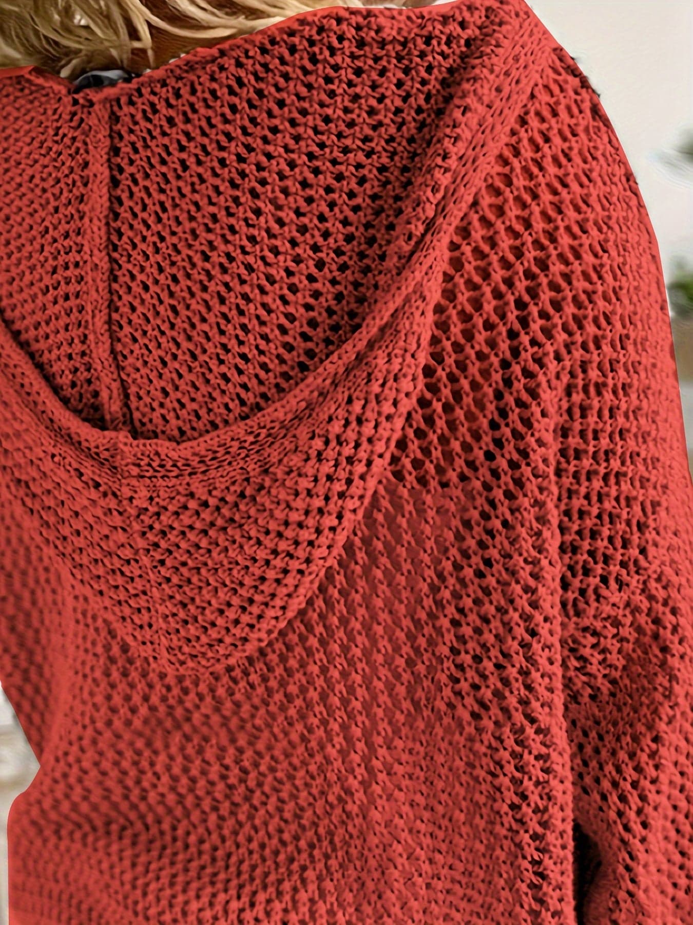 Kvinde iført en løst strikket sweater med åben struktur og hætte, stylet over en hvid bluse_6
