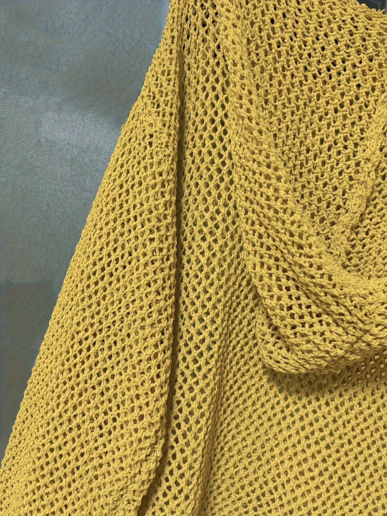 Kvinde iført en løst strikket sweater med åben struktur og hætte, stylet over en hvid bluse_8