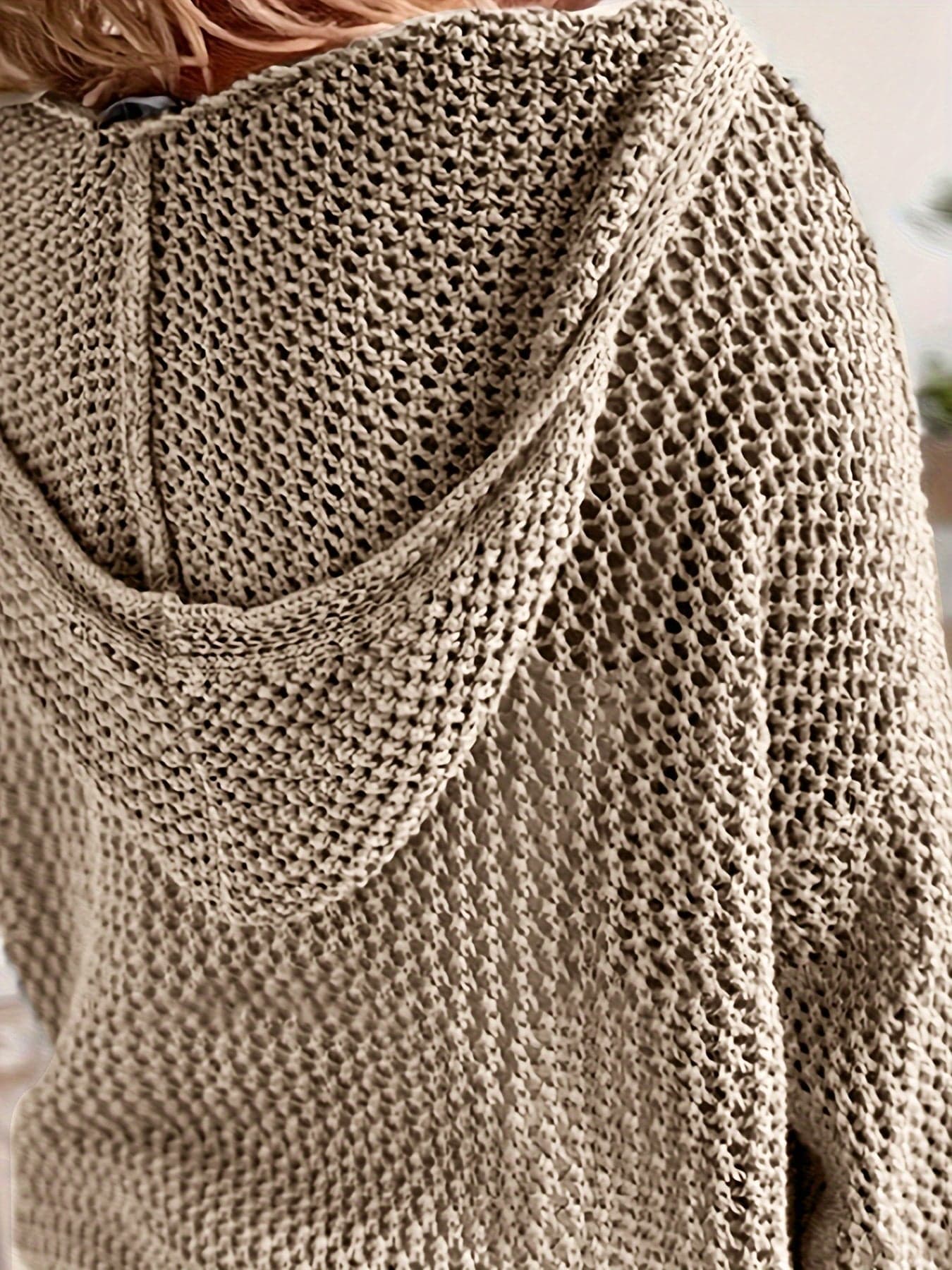 Kvinde iført en løst strikket sweater med åben struktur og hætte, stylet over en hvid bluse_9