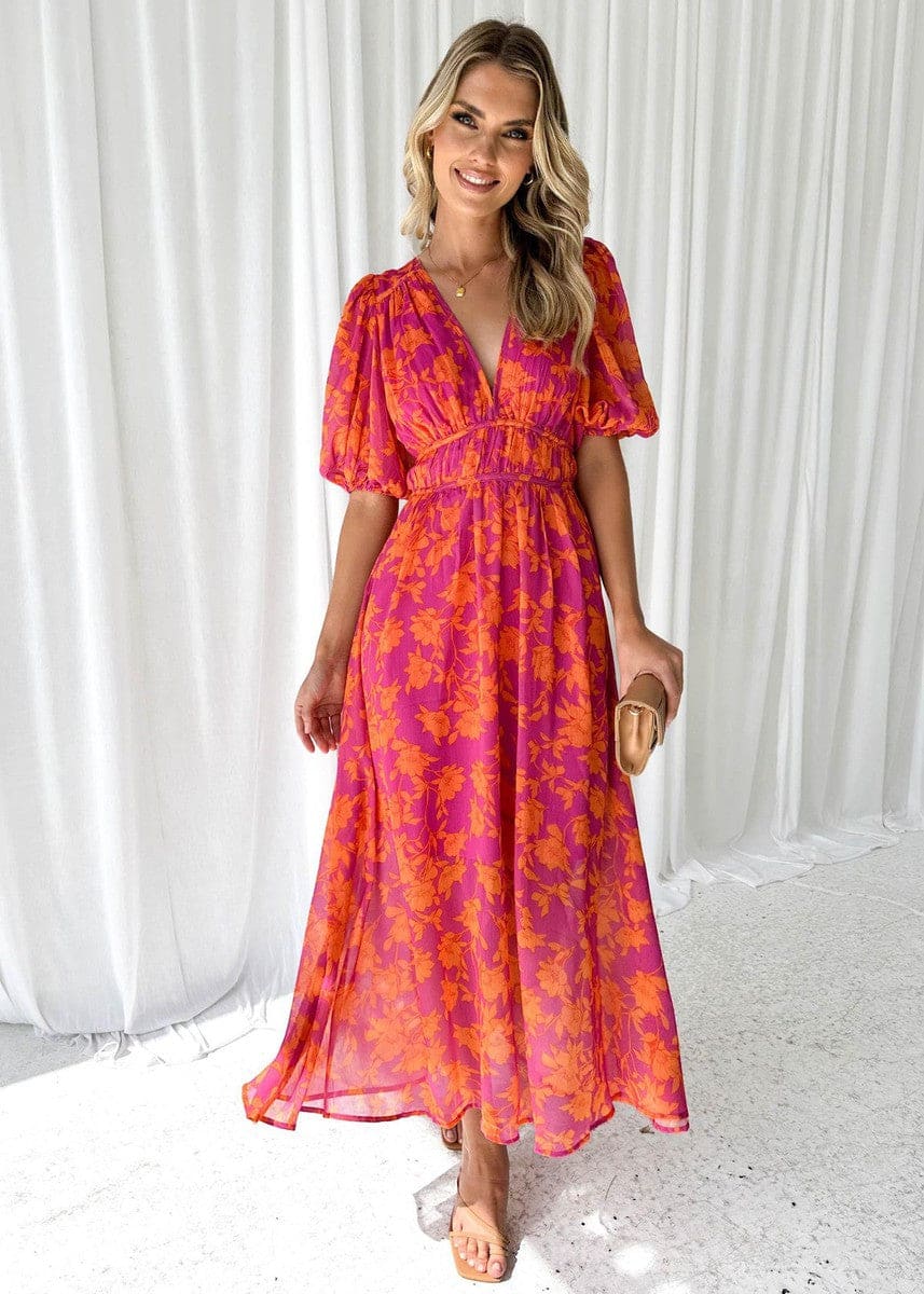 Kvinde iført en maxi kjole med orange og pink blomsterprint, v-udskæring og ballon-ærmer, perfekt til bryllup og festlige begivenheder._0