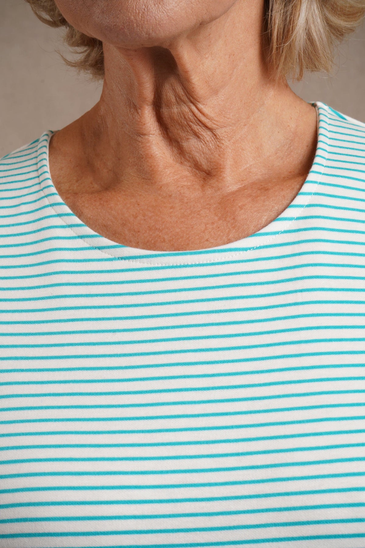 Kvinde i stribet bluse med rund hals og trekvartlange ærmer, båret til jeans._3