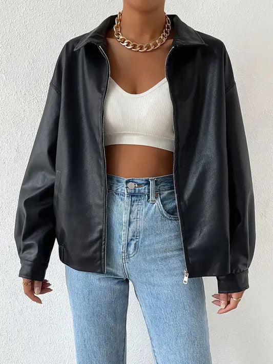 Kvinde iført en oversize jakke med lynlås og krave, stylet med hvid crop top og lyse jeans._0