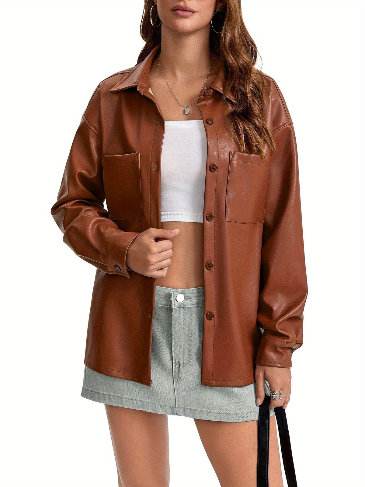 Kvinde iført oversized skjortejakke med krave, knaplukning foran og brystlommer, stylet med brune shorts._8