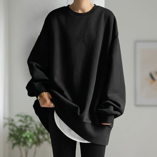 Kvinde iført sort oversized sweatshirt med afslappet pasform, stylet med sorte bukser i moderne skandinavisk interiør_0