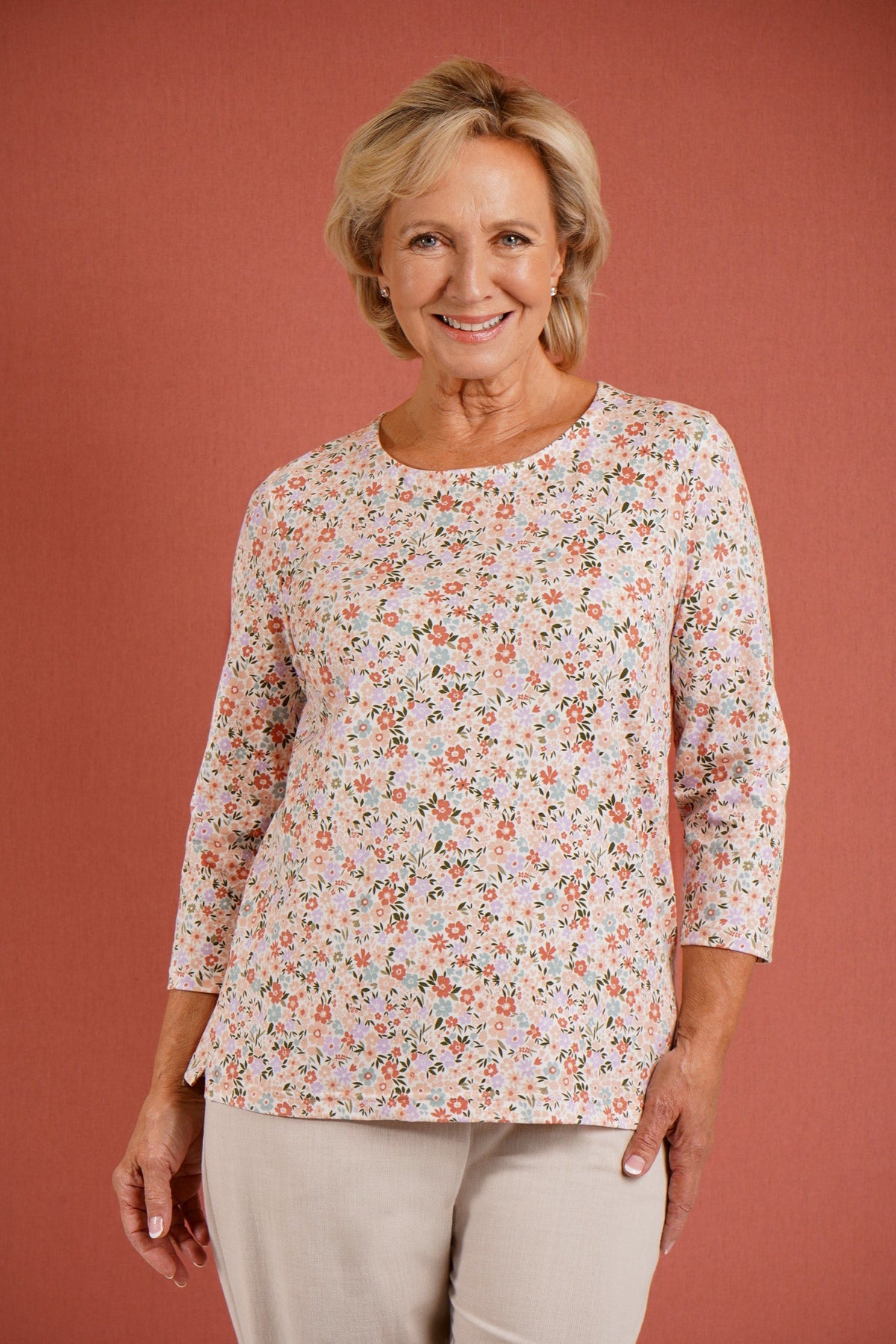 Kvinde i småblomstret bluse med rund hals og 3/4 ærmer, stående i en have._2