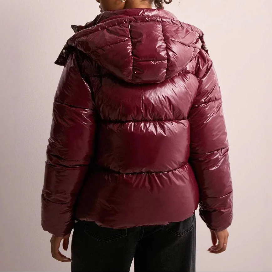 Kvinde iført sort quiltet pufferjakke med hætte og lynlås foran, stylet med hvid top og lyse jeans_4