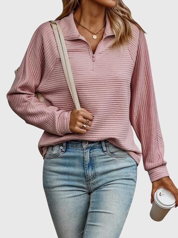 Model iført lys rosa ribstrikket sweater med halvlynlås i halsen og afslappet pasform, kombineret med lyse jeans._0