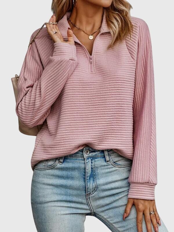 Model iført lys rosa ribstrikket sweater med halvlynlås i halsen og afslappet pasform, kombineret med lyse jeans._1