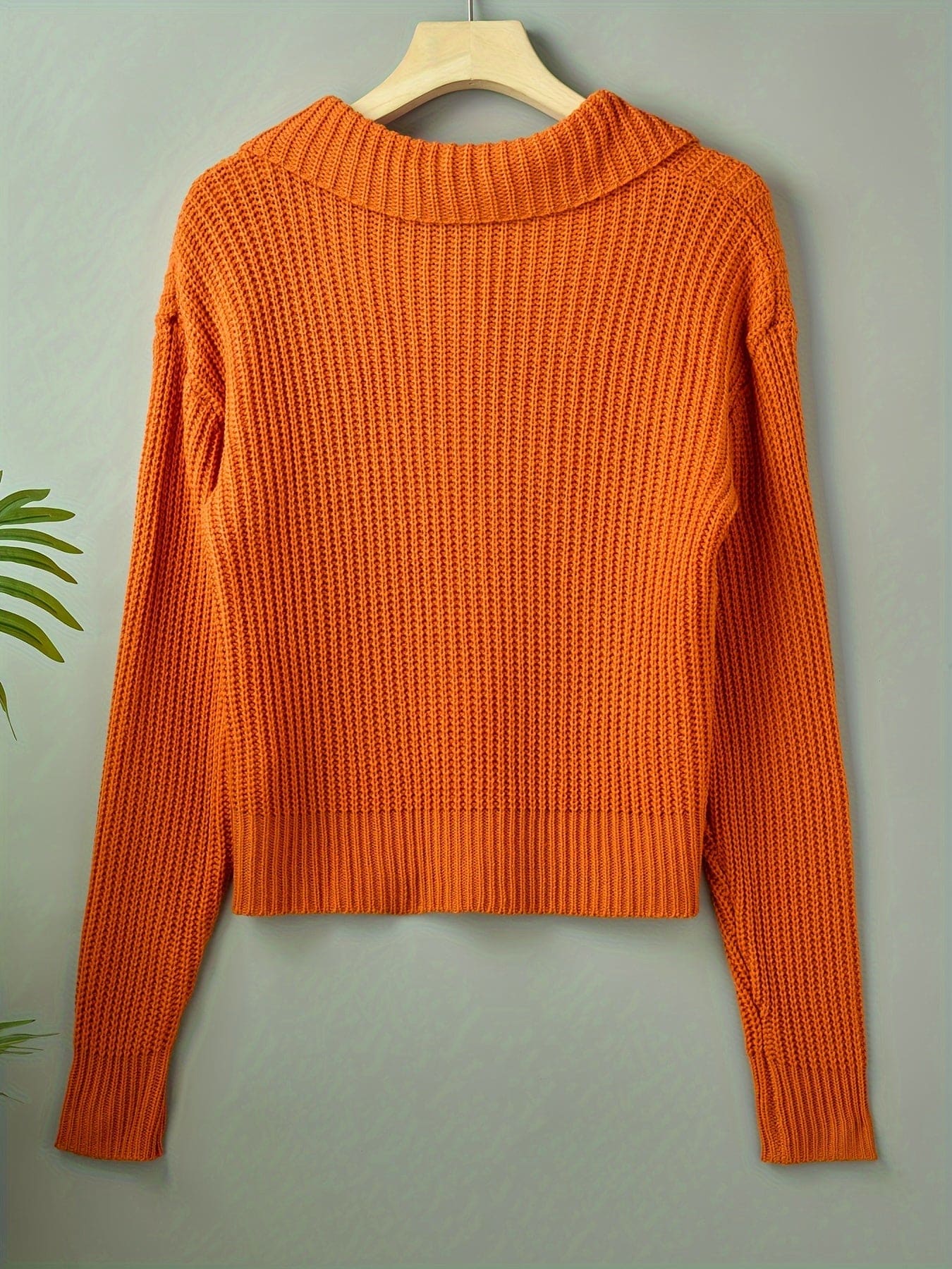 En ribstrikket sweater med rullekrave og afslappet pasform hænger på en bøjle mod lys baggrund._0