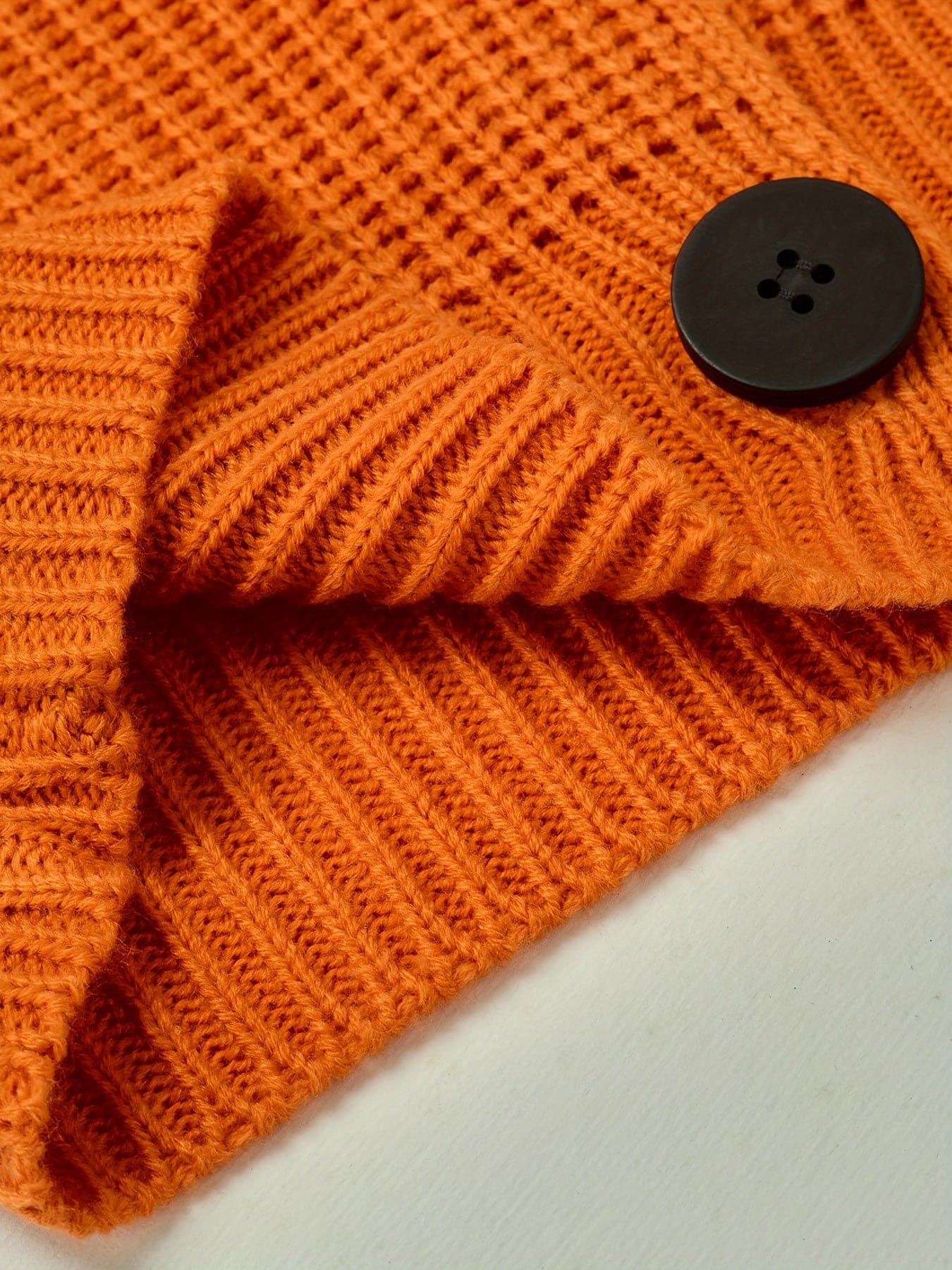 En ribstrikket sweater med rullekrave og afslappet pasform hænger på en bøjle mod lys baggrund._4