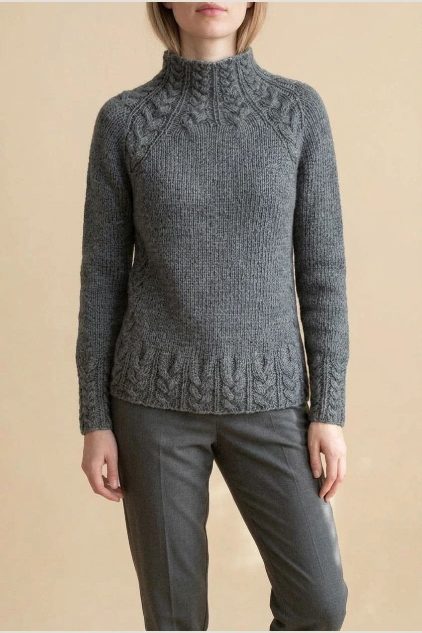 Kvinde i strikket sweater med høj hals, raglanærmer og snoningsmønster ved skuldre og nederste kant._0