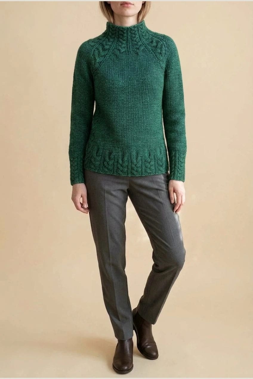 Kvinde i strikket sweater med høj hals, raglanærmer og snoningsmønster ved skuldre og nederste kant._7