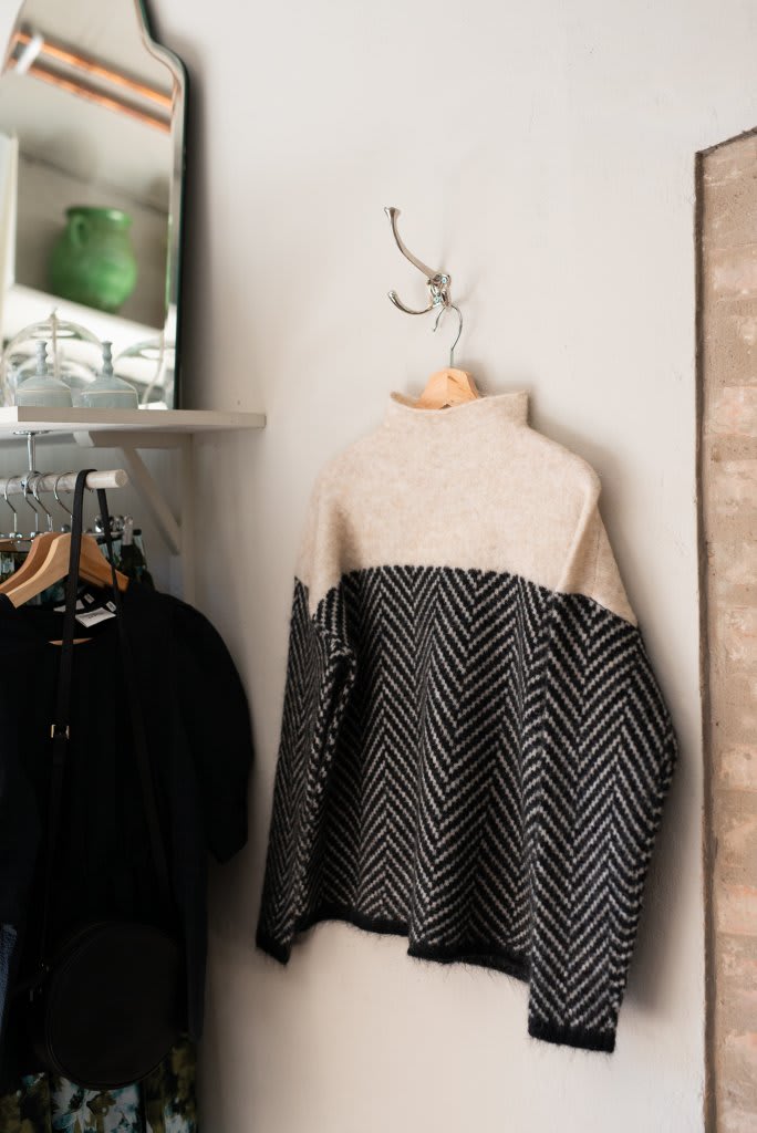 Kvinde iført en beige og sort sweater med rullekrave og chevron-mønster, stylet med lyse jeans._3
