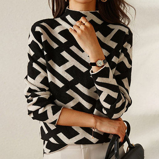 Kvinde iført sort-beige rullekrave sweater med grafisk mønster, fotograferet fra fronten med hænderne ved brystet._0