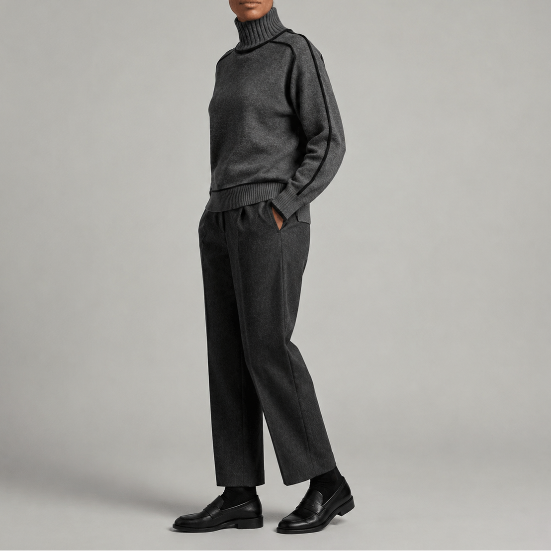 Kvinde iført en cremefarvet sweater med rullekrave og sorte kontrastdetaljer, stylet med hvide bukser._4