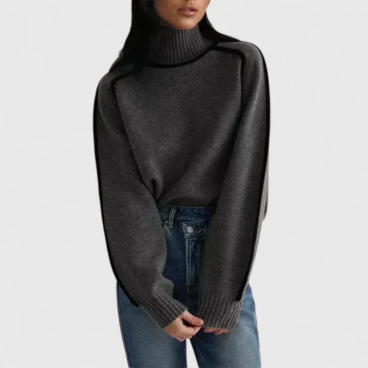Kvinde iført en brun rullekrave sweater med kontrasterende sorte kantsømme, stylet med lyse bukser og et bælte._1