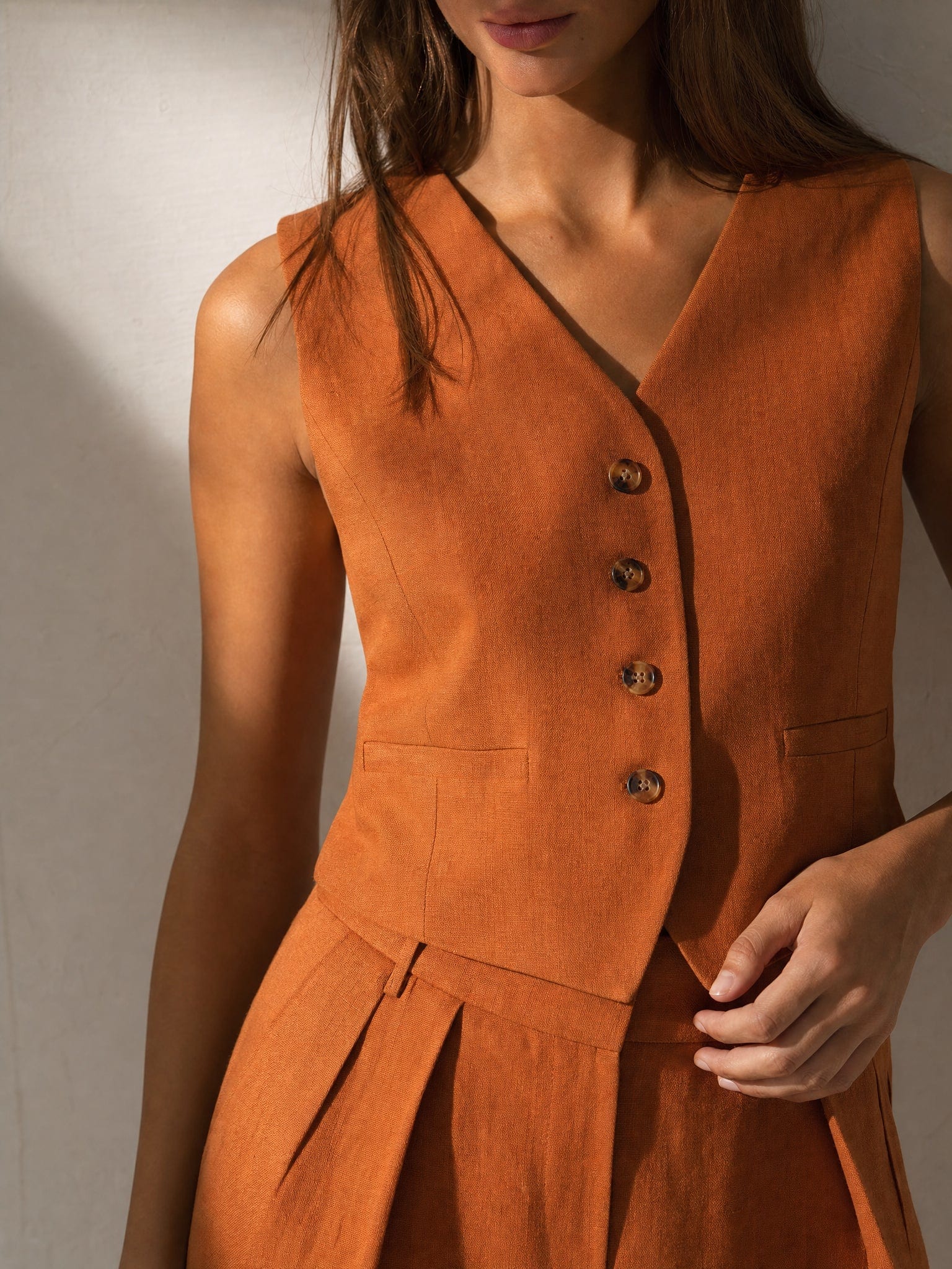 Kvinde iført todelt sæt bestående af vest med knapper og wide-leg bukser i beige nuancer, fotograferet i minimalistisk interiør_4
