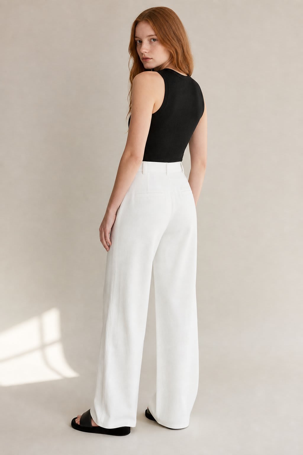 Kvinde iført lyse wide-leg bukser i høj talje, skræddersyet pasform, med cropped top og blazer._1