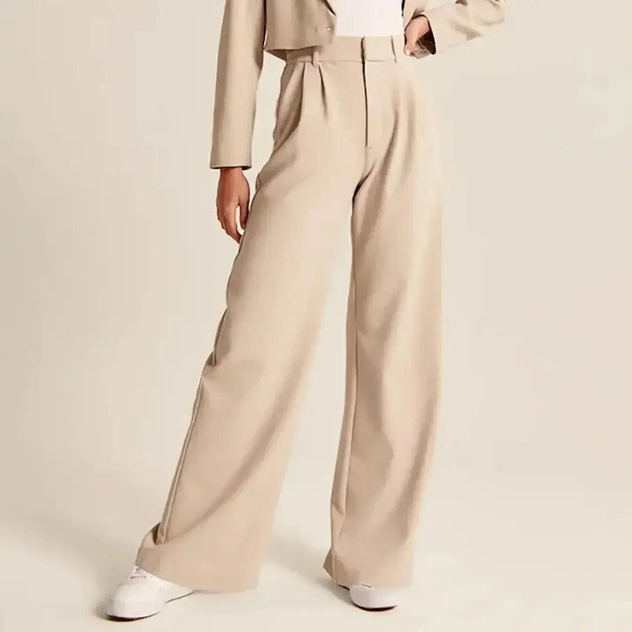 Kvinde iført lyse wide-leg bukser i høj talje, skræddersyet pasform, med cropped top og blazer._13